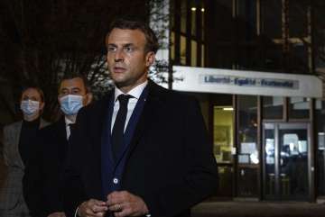 French President Emmanuel Macron, flanked by French Interior Minister Gerald Darmanin, second left, speaks in front of a high school Friday Oct.16, 2020 in Conflans Sainte-Honorine, northwest of Paris, after a history teacher who opened a discussion with high school students on caricatures of Islam's Prophet Muhammad was beheaded. French President Emmanuel Macron denounced what he called an "Islamist terrorist attack" against a history teacher decapitated in a Paris suburb Friday, urging the nation to stand united against extremism.