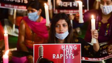 People hold placards during their candlelight vigil demanding justice for Hathras victim in New Delhi on October 12. (FILE PHOTO)