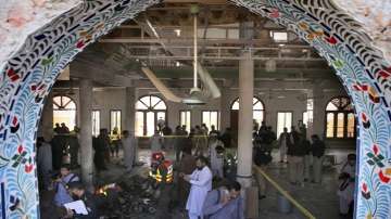 Pakistani rescue workers and police officers examine the site of a bomb explosion in an Islamic seminary, in Peshawar, Pakistan