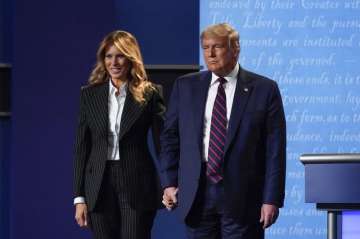 President Donald Trump and first lady Melania Trump hold hands on stage after the first presidential