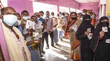 ?Voters show their identity cards as they stand in queues at a polling station to cast their votes for the first phase Bihar Assembly Elections, at Paliganj in Patna