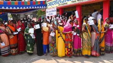 Voters show their identity cards as they stand in a queue to cast their votes for the first phase of Bihar Assembly Elections, at Imamganj in Gaya.