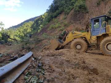 A bulldozer clears out the road damaged by landslide to access a village swamped by another landslid