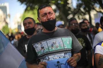 A man cries as he waits in a line outside the presidential palace to pay his final respects to Diego Maradona, in Buenos Aires, Argentina, Thursday, Nov. 26