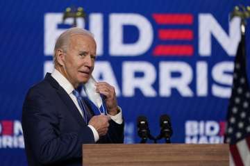 Democratic presidential candidate former Vice President Joe Biden removes his face mask as he arrives to speak, Friday, Nov. 6, 2020, in Wilmington, Del.