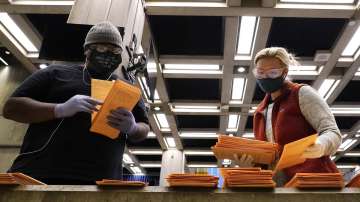 Election officials sort absentee and early voting ballots for counting inside Boston City Hall, Mond