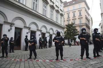 Police officers guard the scene in Vienna after several shots were fired on Monday in a lively stree