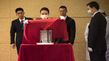 A staff member places a cover over a container of soil and rocks from the moon during a handover ceremony for lunar samples collected by Chinas Change 5 lunar lander at the China National Space Administration in Beijing.