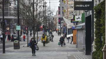 A woman wears a face mask as she walks in a near empty Oxford Street, in London. Britain's Prime Minister Boris Johnson cancelled Christmas for almost 18 million people across London and eastern and south-east England, following warnings from scientists of the rapid spread of the new variant of coronavirus.