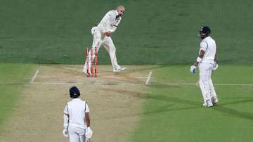 Nathan Lyon clips off the bails while Virat Kohli is in the middle.