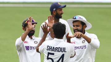 India's Ajinkya Rahane, left, and India's Rohit Sharma, right, congratulate teammate Shardul Thakur, centre, after dismissing Australia's Tim Paine during play on day four of the fourth cricket test between India and Australia at the Gabba, Brisbane, Australia, Monday, Jan. 18