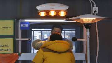 A medical worker in a booth takes a sample from a man at a coronavirus testing site in Seoul, South Korea.