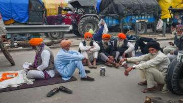 Farmers take rest during their ongoing protest against the new farm laws, at Singhu border in New De