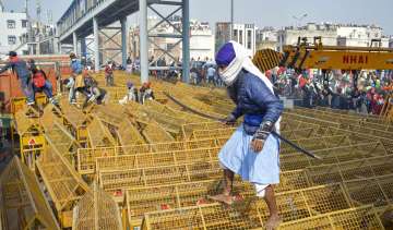 A farmer walks over the police barricades set up on a road at Akshardham to stop farmers during thei