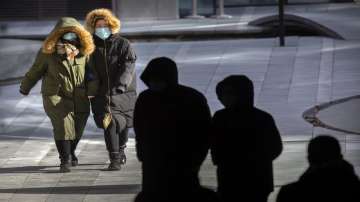 People wearing face masks to protect against the coronavirus walk on an unseasonably cold day at an 