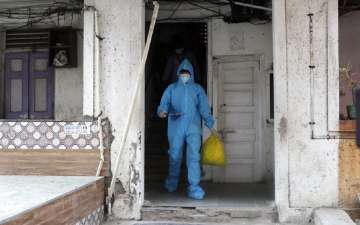 A health worker comes out of a residential building during a door to door screening for COVID-19 peo