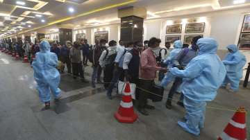 Passengers line up to get their temperatures checked at a train station in Mumbai.