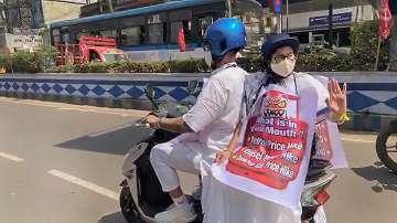 West Bengal Chief Minister Mamata Banerjee rides pillion on an electric scooter to reach Nabanna (State Secretariat) during a protest against the hike in fuel price, in Kolkata.