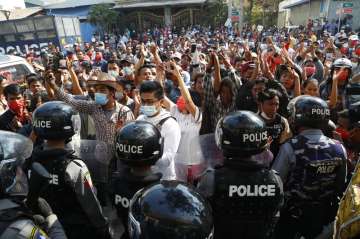 Residents and protesters face riot police as they question them about recent arrests made in Mandala