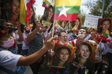 Myanmar nationals living in Thailand hold pictures of deposed Myanmar leader Aung San Suu Kyi as the