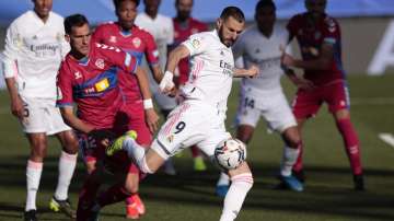 Real Madrid's Karim Benzema kicks the ball next to Elche's Dani Calvo during the Spanish La Liga soccer match between Real Madrid and Elche at the Alfredo di Stefano stadium in Madrid, Spain, Saturday, March 13