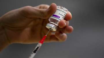 A pharmacist prepares a syringe from a vial of the AstraZeneca coronavirus vaccine.