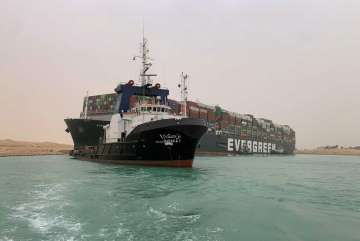 Suez Canal Authority, a boat navigates in front of a cargo ship, Ever Given, Wednesday, March 24, 20