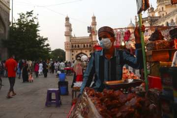 A vendor wearing a face mask as a precaution against coronavirus waits for customers while selling dates in front of Mecca Masjid in Hyderabad