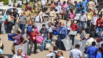 Polling officials carry Electronic Voting Machines (EVMs) and other materials as they leave for polling stations from a distribution centre on the eve of the third and final phase of State Assembly elections, in Guwahati.