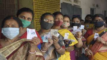 Women show their voter ID card, as they stand in a queue to cast their vote at a polling station during the 5th phase of West Bengal State Assembly polls.