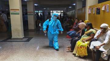 An Indian woman in personal protective suit walks towards a COVID-19 ward of a hospital as others waits for their test results.