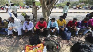 Migrant workers from Bihar state wearing face masks wait for a train at Lokmanya Tilak railway station in Mumbai.