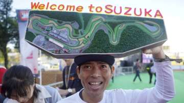 In this Sunday, Oct. 13, 2019 file photo, a fan with a model of Suzuka Circuit waits for drivers in front of the gate of the paddock ahead of the Japanese Formula One Grand Prix in Suzuka, central Japan.