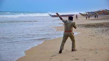 A police person announces cyclone related warnings at a beach in Puri, Saturday. Cyclone Yaas is likely to intensify into a very severe cyclonic storm and cross the Odisha and the West Bengal coasts on May 26.