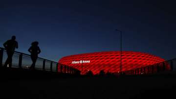 In this March 16, 2020 taken photo jogger make their way after the sun sets at the 'Allianz Arena' soccer stadium in Munich, Germany.