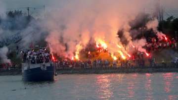 A boat with players cruises on Sava river as Red Star fans celebrate after their team won the Serbian soccer league title in Belgrade, Serbia, Saturday, May 22