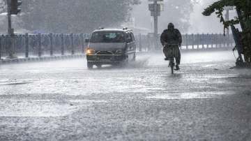 A man pedals through heavy rain.
