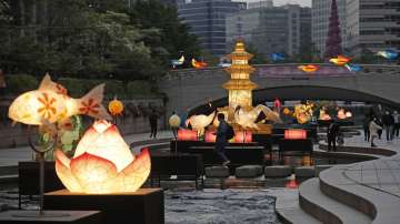 Visitors wearing face masks as a precaution against the spread of the coronavirus walk near lanterns displayed for the upcoming celebration of Buddhas birthday on May 19 at the public stream in Seoul, South Korea.