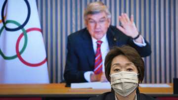 In this April 28, 2021, file photo, IOC President Thomas Bach, on a screen, waves to Tokyo 2020 Organizing Committee President Seiko Hashimoto at the start of a five-party meeting of Tokyo 2020 Olympic and Paralympic Games in Tokyo.