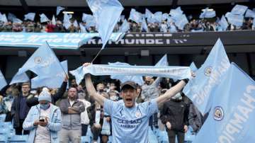 Fans celebrate the start of the English Premier League soccer match between Manchester City and Everton at the Etihad stadium in Manchester, Sunday, May 23