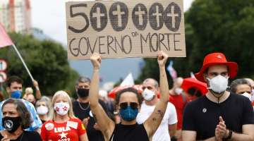 A woman wearing a face mask holds a sign with a message that reads in Portuguese: "500,000, government of death" during a protest against Brazilian President Jair Bolsonaro's handling of the coronavirus pandemic, in Rio de Janeiro on Saturday