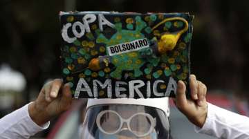 A woman holds a sign to protest against Brazil holding the Copa America in Brasilia, Brazil, Sunday, June 6, 2021.