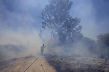 An Israeli firefighter attempts to extinguish a fire caused by an incendiary balloon launched by Palestinians from the Gaza Strip on the Israel-Gaza border on June 15, 2021