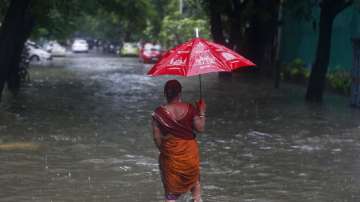 A woman walks through a flooded street during heavy rains.