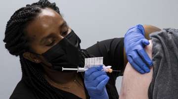 FILE - In this Wednesday, March 31, 2021 file photo, Cole Smith receives a Moderna variant vaccine shot from clinical research nurse Tigisty Girmay at Emory University's Hope Clinic in Decatur, Ga