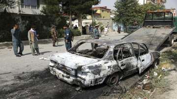 Security personnel inspect a damaged vehicle where rockets were fired from in Kabul, Afghanistan.