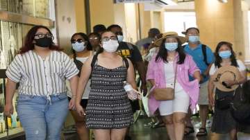 Visitors wear masks as they walk in a shopping district, in the Hollywood section of Los Angeles. Coronavirus cases have jumped 500% in Los Angeles County over the past month and health officials warned Tuesday.