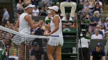 Australia's Ashleigh Barty, right, holds hands with Czech Republic's Barbora Krejcikova after winning the women's singles fourth round match on day seven of the Wimbledon Tennis Championships in London, Monday, July 5