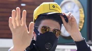 In this March 12, 2020, file photo Renault driver Esteban Ocon of France waves as he arrives wearing a mask to the Australian Formula One Grand Prix in Melbourne.