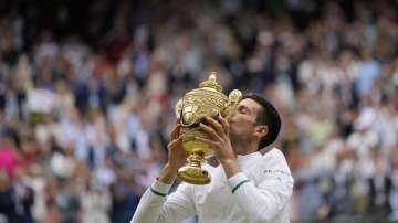 Serbia's Novak Djokovic kisses the winners trophy as he poses for photographers after he defeated Italy's Matteo Berrettini in the men's singles final on day thirteen of the Wimbledon Tennis Championships in London, Sunday, July 11